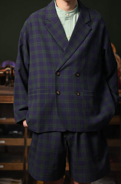 Person wearing a double-breasted tartan suit with a blurred background
