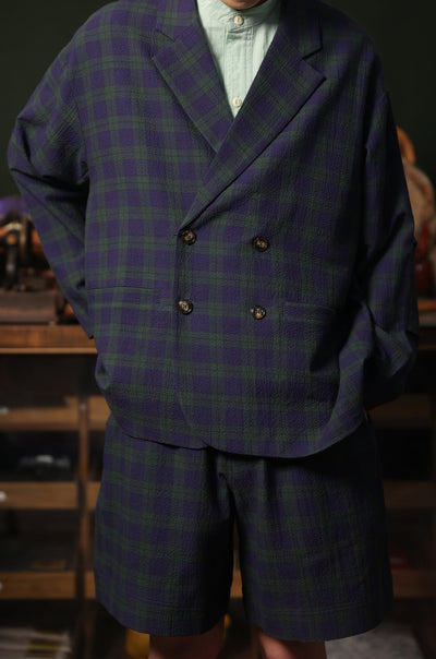 Person wearing a double-breasted tartan jacket and shorts in a casual setting.