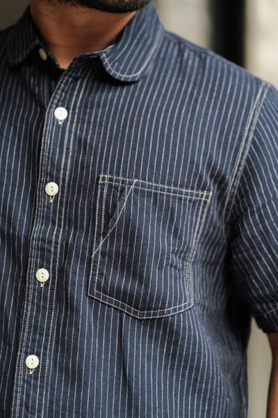 Close-up of a person wearing a blue and white striped shirt with a pocket.