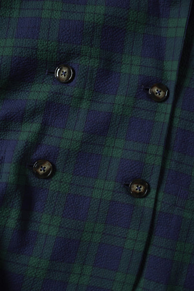 Close-up of a green and blue plaid fabric with buttons on a gray background