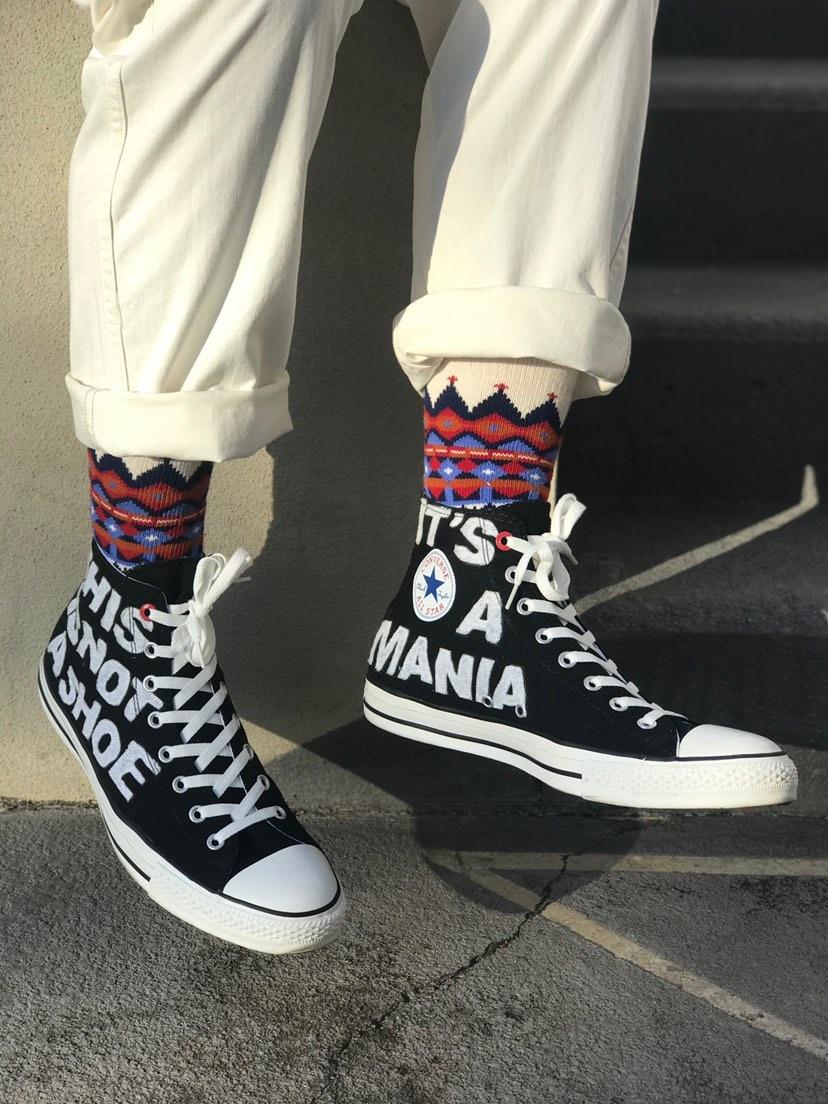 Thick white cotton crew socks with tribal patterns paired with black Converse shoes.